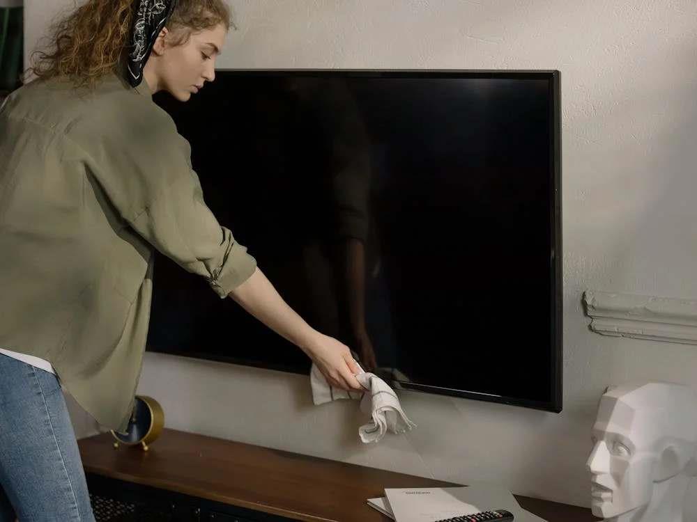 Woman cleaning a thin television set