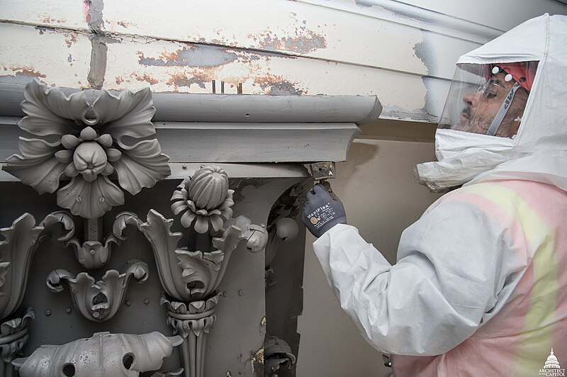 A worker carefully removing lead paint