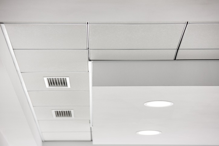 Multi-level gypsum plasterboard ceiling and a white square tile suspended ceiling with integrated lighting lamps and ventilation grilles