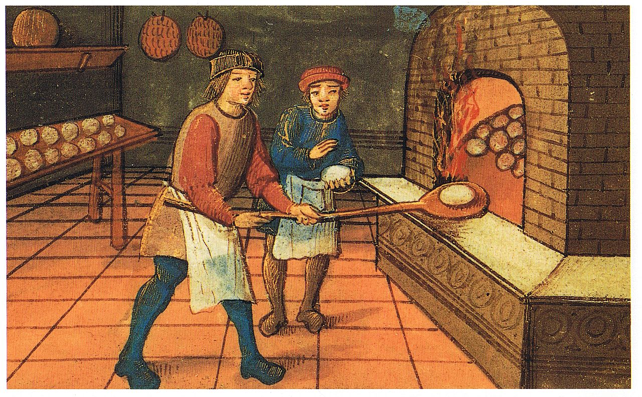 a baker with an assistant in medieval times baking bread