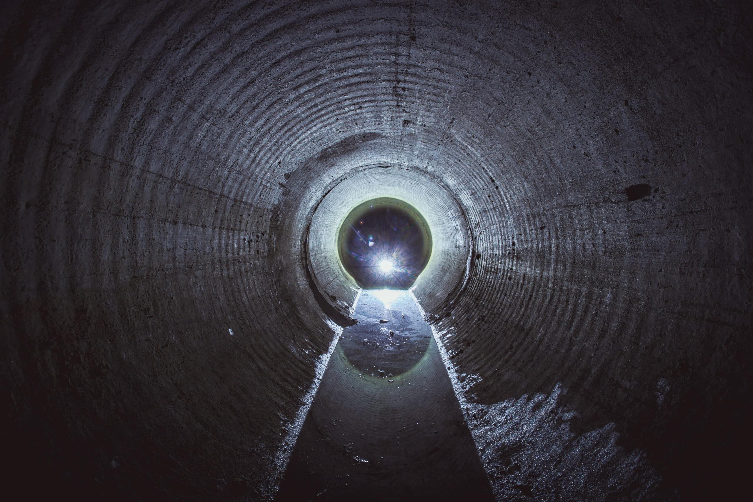 Flooded round underground drainage sewer tunnel with dirty sewage water