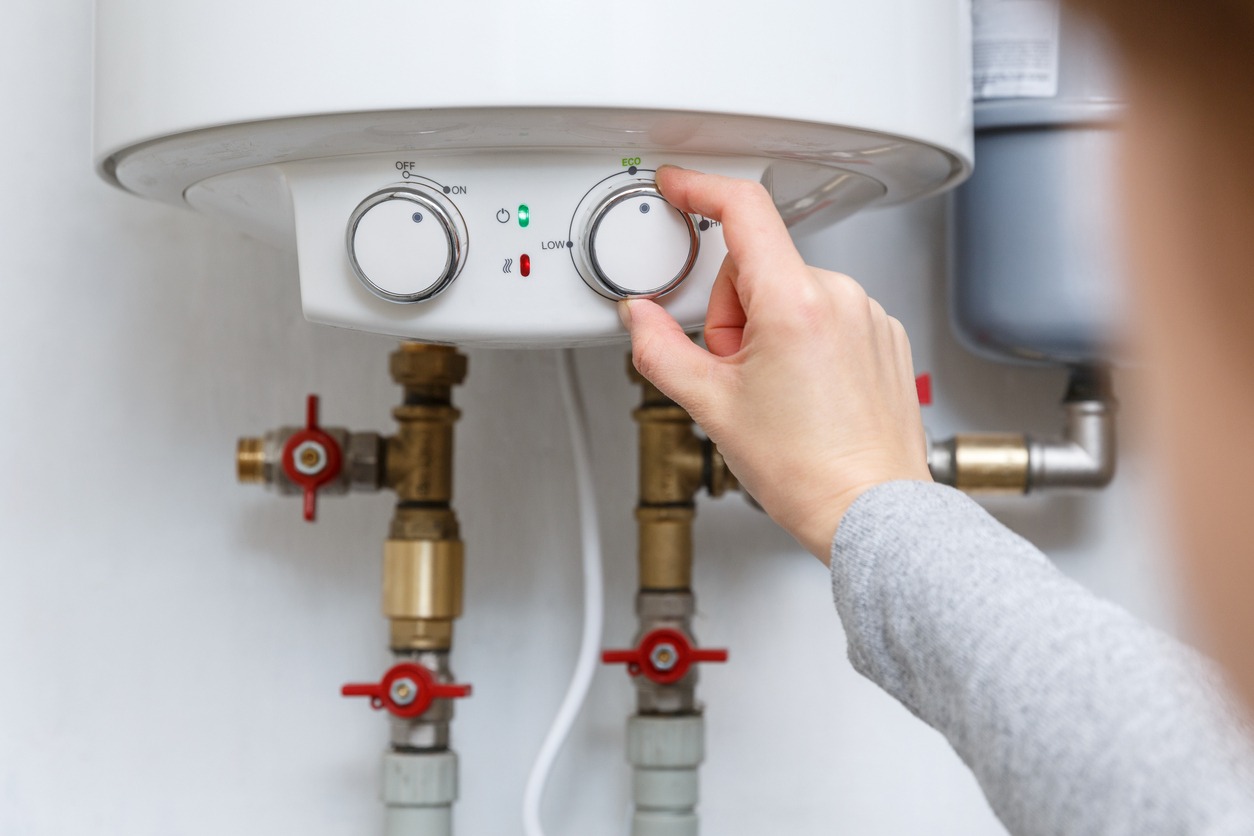 Female hand puts thermostat of electric water heater (boiler) in economy mode.