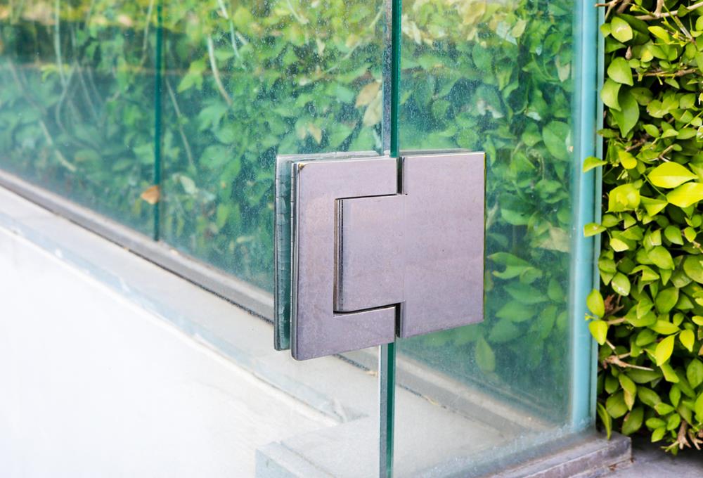 A stainless steel hinge fitting on glass