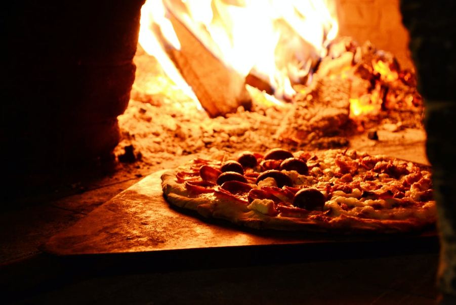 Pizza on a wood platter near a bonfire