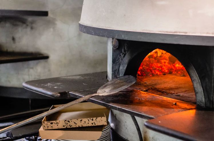 Image of a pizza peel and pizza oven in a restaurant.