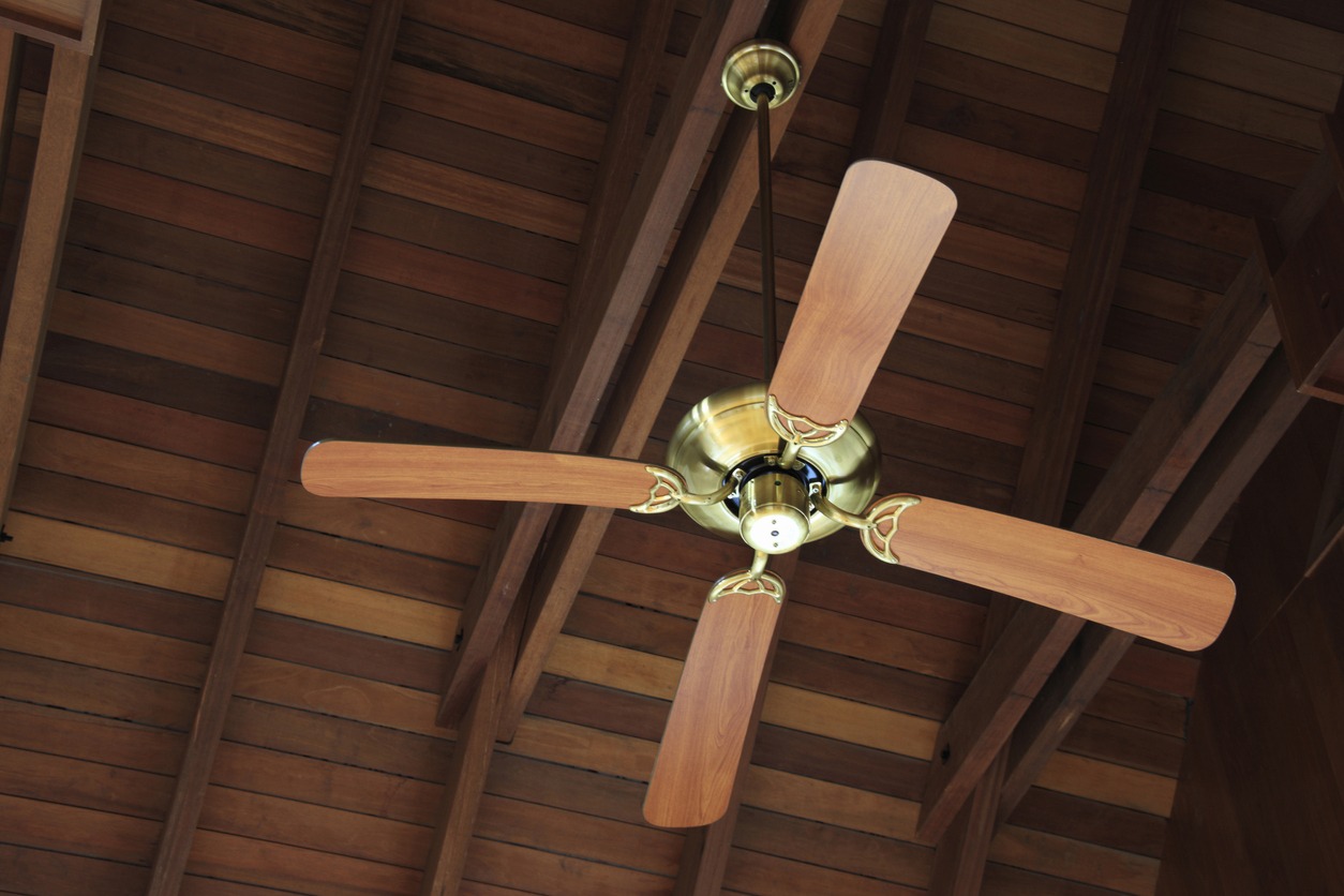 a standard ceiling fan with wooden blades suspended on the ceiling