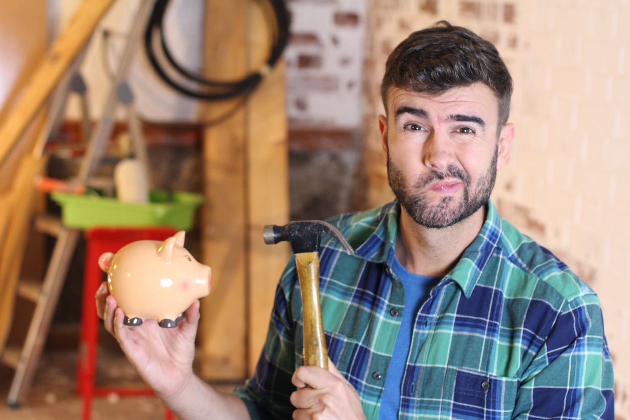 Man breaking piggy bank to do home renovations