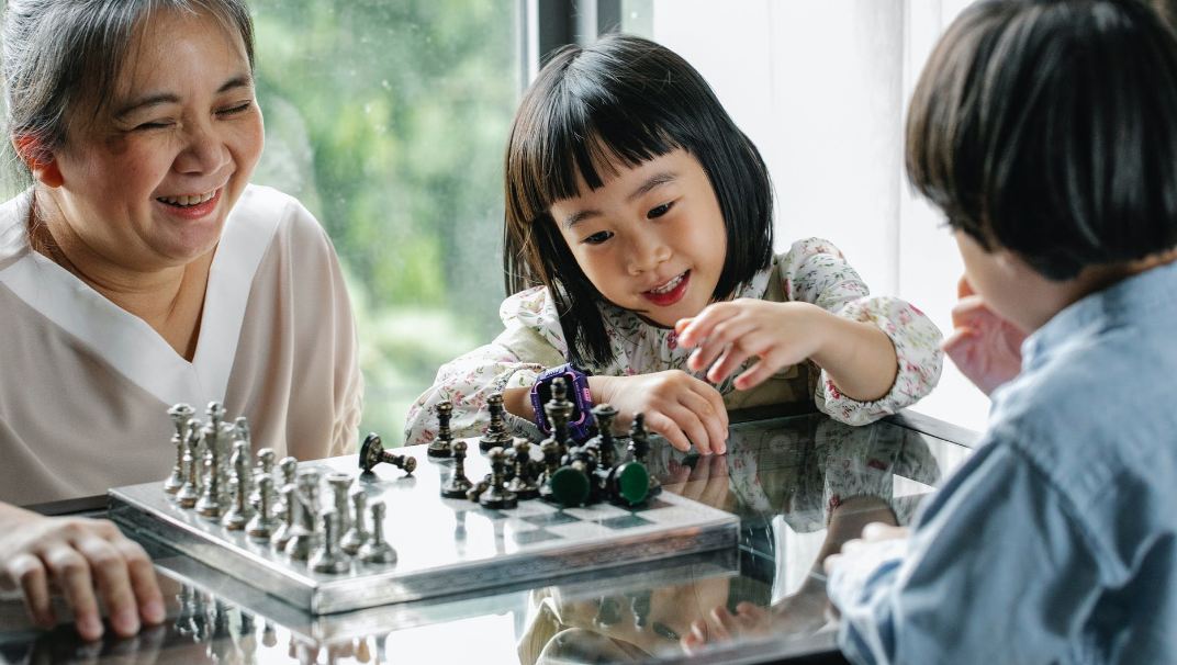 Image showing a child making a move while playing chess with their grandmother.