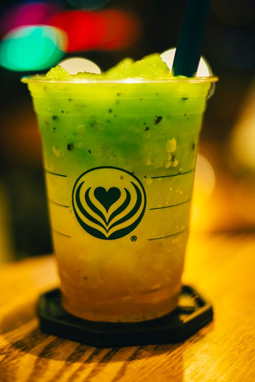 Image showing a clear plastic cup with green-yellow slushie in it. 