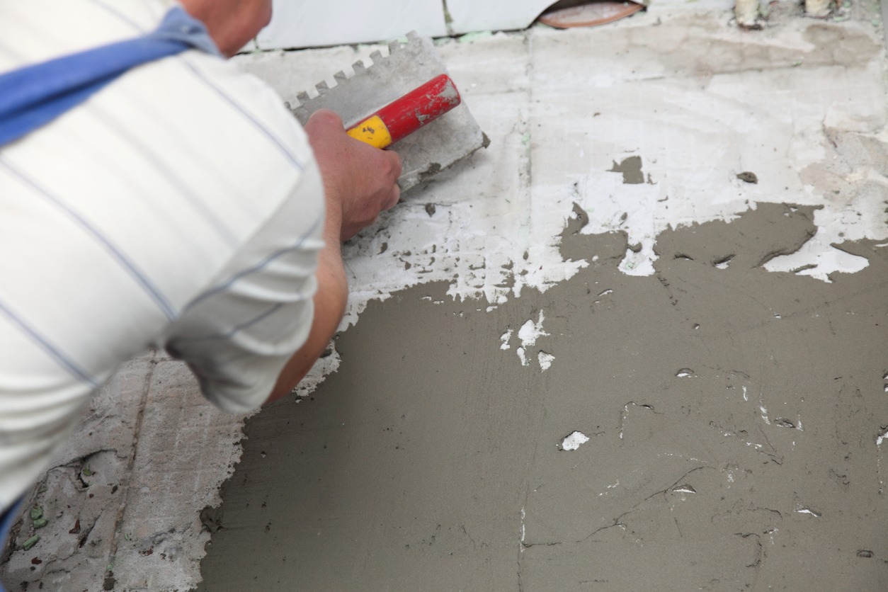 Construction worker is tiling at home tile floor adhesive