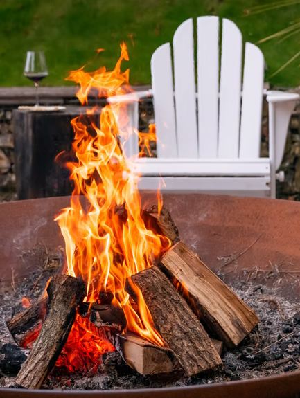 A fire pit in the backyard with an Adirondack chair in the backyard