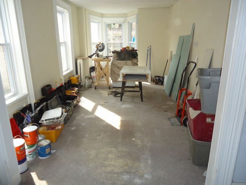A room with all furniture cleared up and renovation tools and materials set up