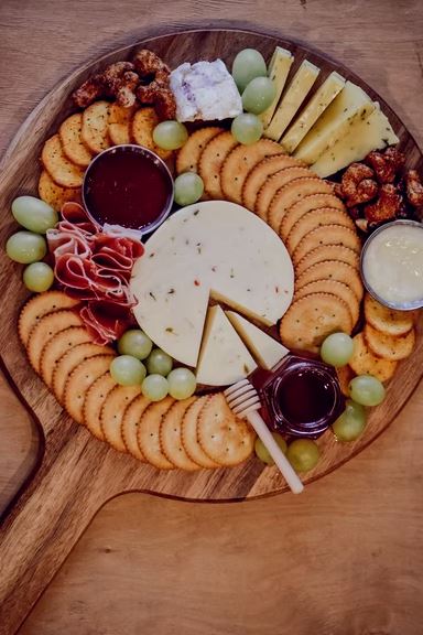 A round cheese board with meats and crackers