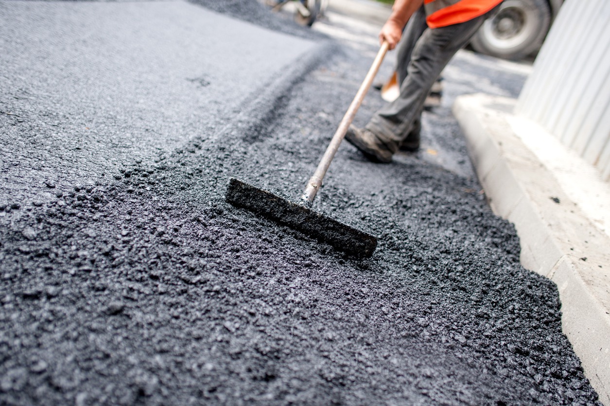 Worker levelling fresh asphalt on a road construction site