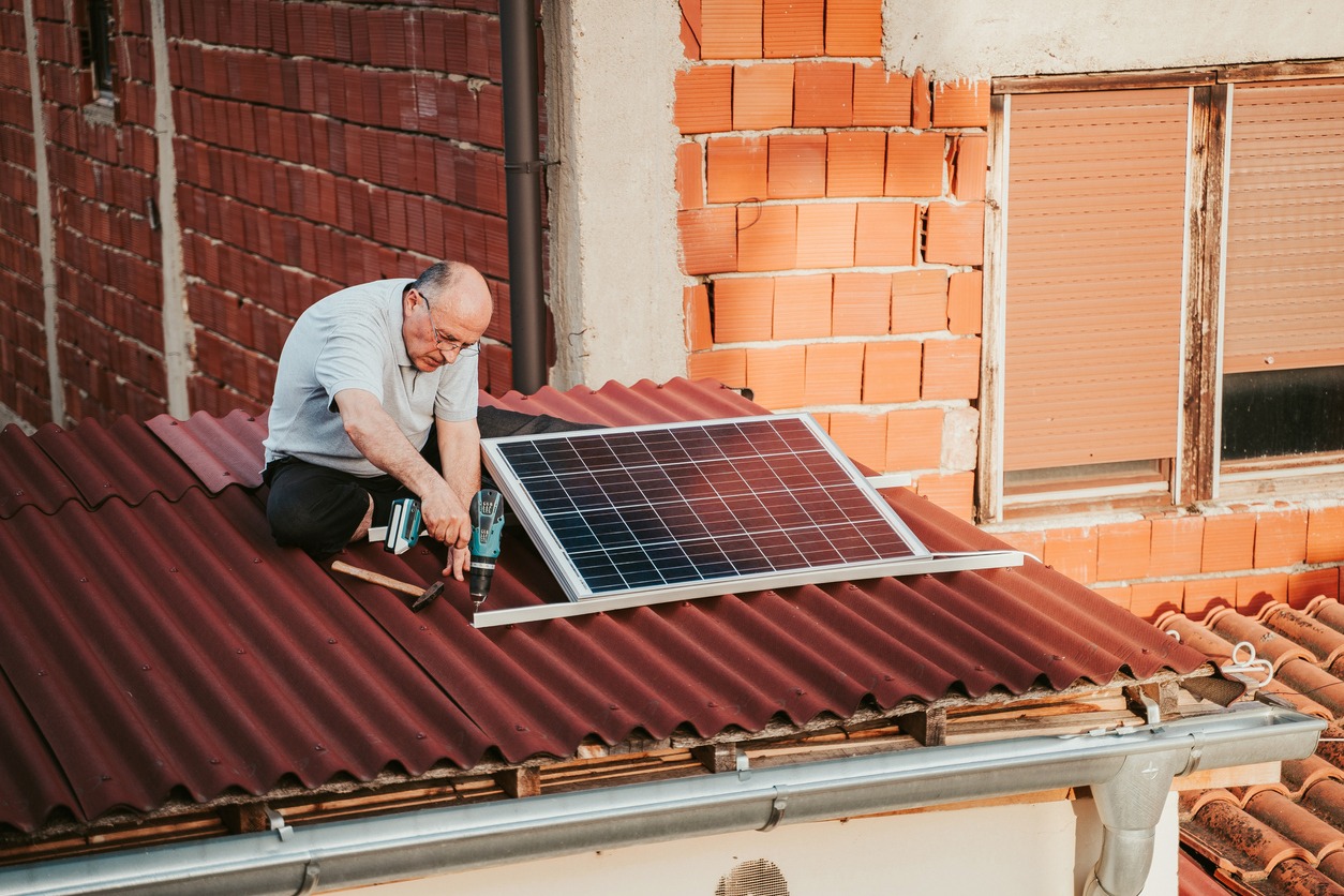 Senior man installing solar panel