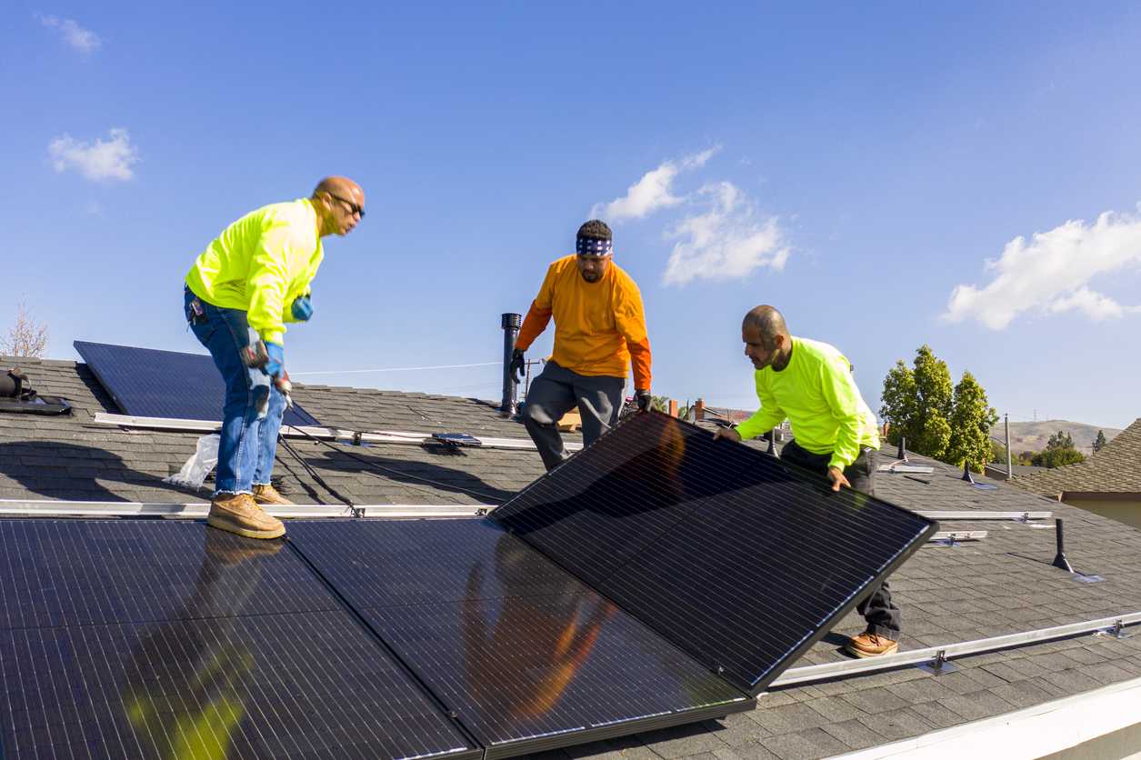 Team of Workers Installing Solar Panels on Residential Rooftop in California