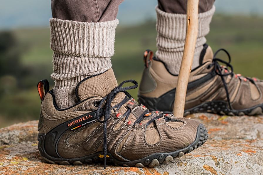 the feet of a person wearing gray socks and hiking shoes holding a stick