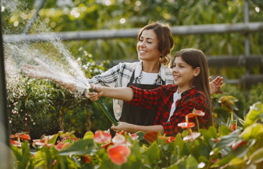 mom and daughter watering the plants together