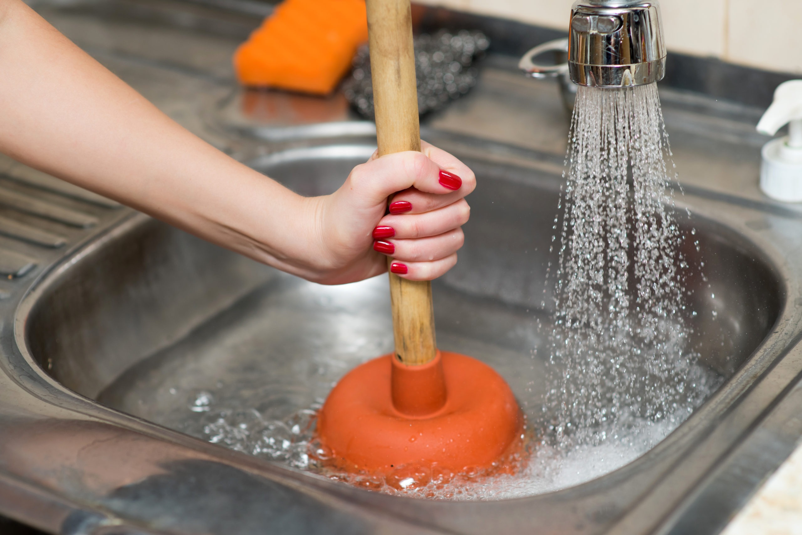 woman cleans plunger with clogged sink