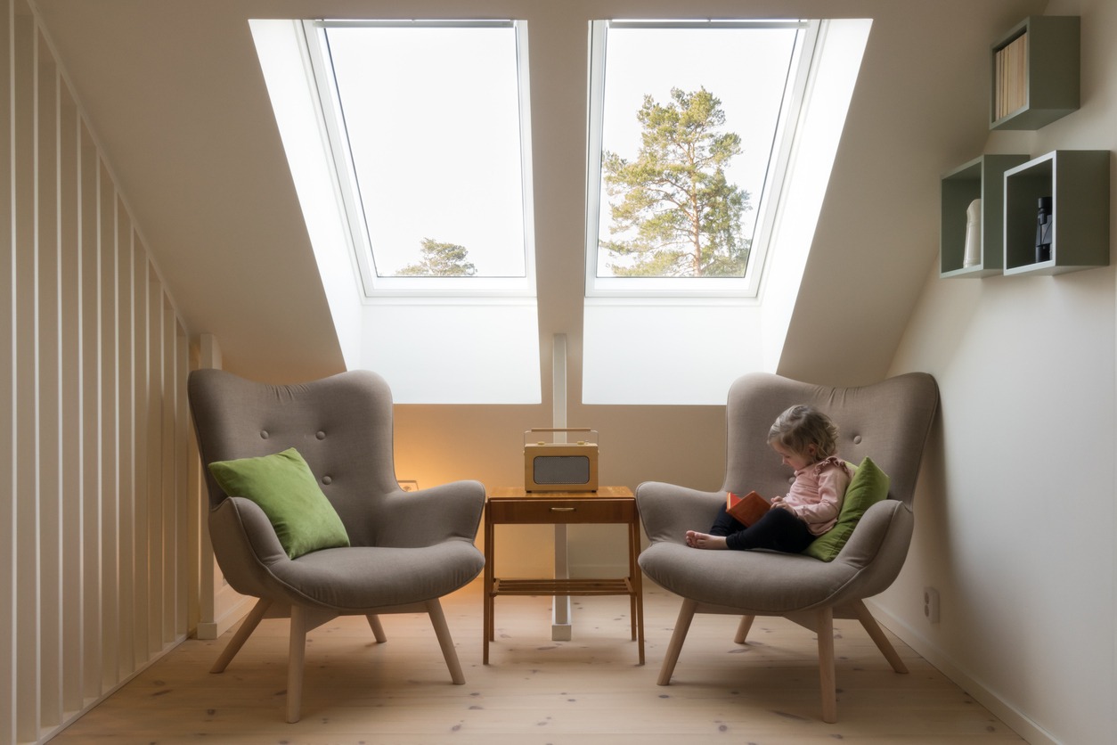 Small child reading a book under a skylight