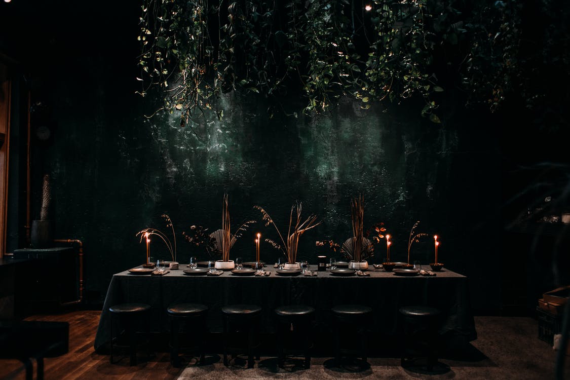 a dark room with plants hanging over a table setup