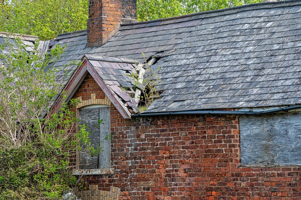 Damaged slate roof tiles on a pitched roof