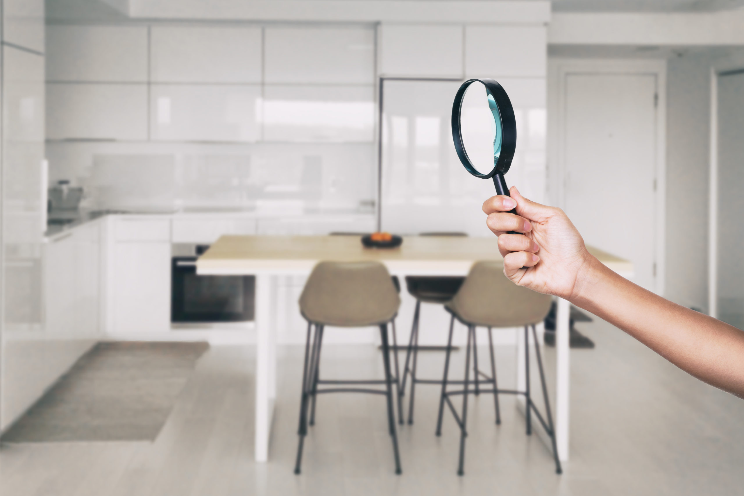 Home inspection - magnifying glass inspector looking at kitchen house background.