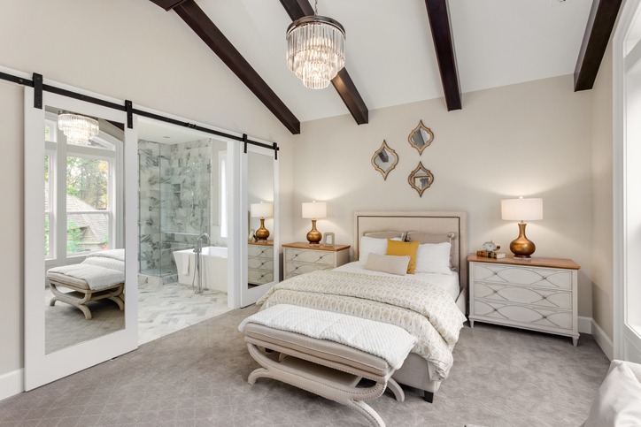 Master bedroom in new luxury home with chandelier and view of bathroom