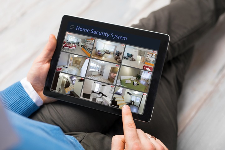 Man looking at home security cameras on tablet computer