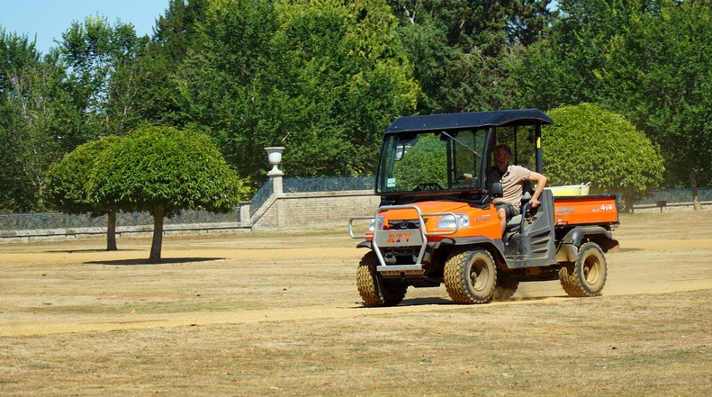 Gardener driving Kubota RTV900 4X4 utility vehicle in park land.