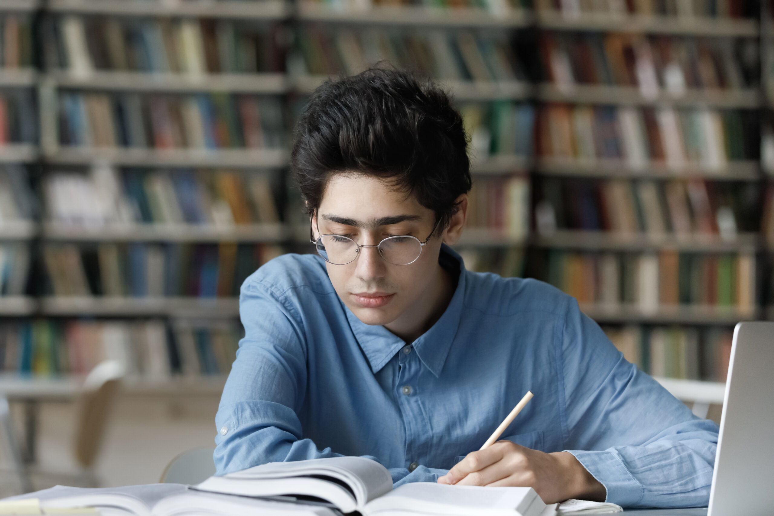 Focused busy young male Jewish student studying in library.