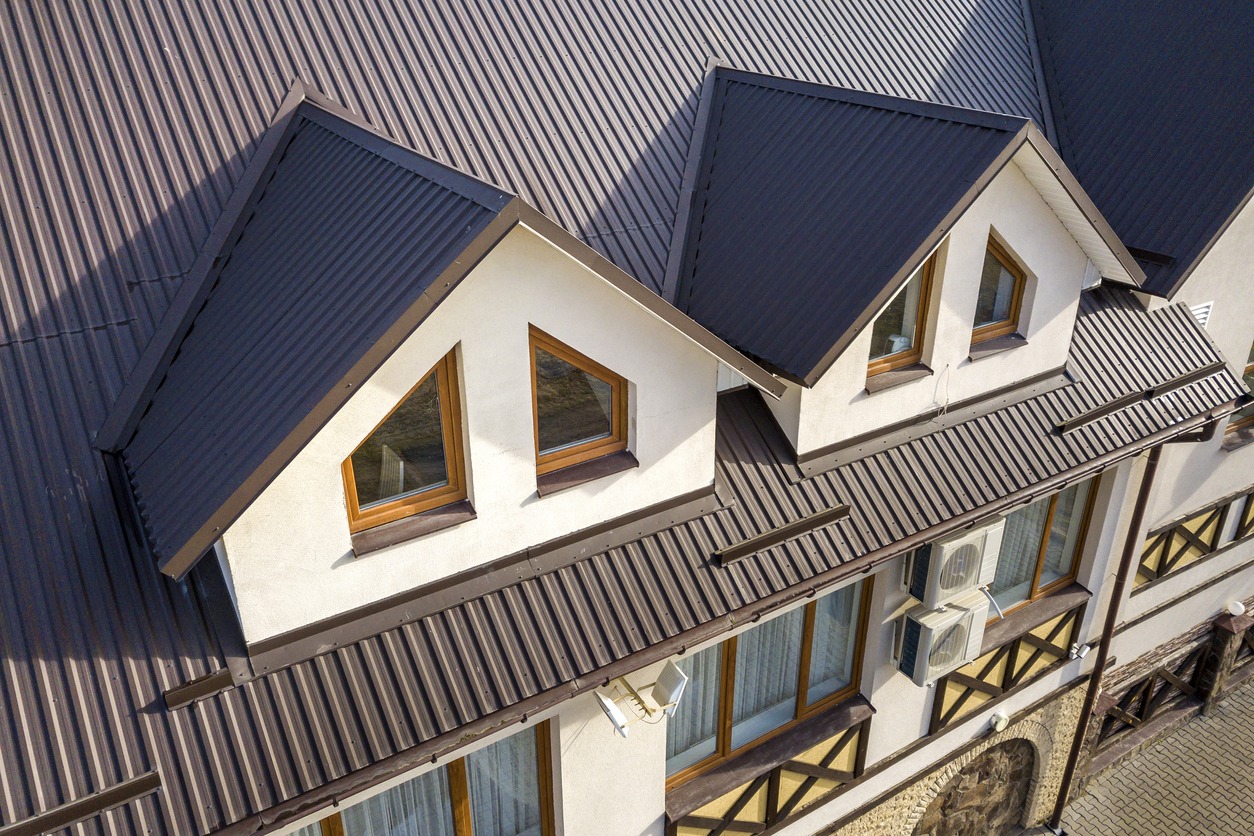 Close-up aerial view of building attic rooms exterior on metal shingle roof