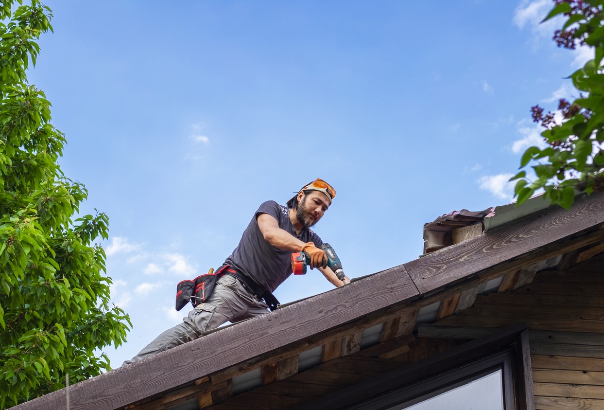 a man using an electric screwdriver while working on a roof