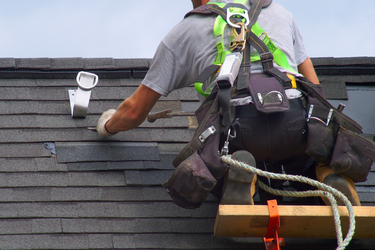 a roofer man wearing a safety harness