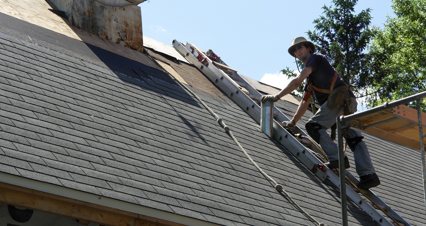 two roofers installing asphalt shingles during new residential house construction