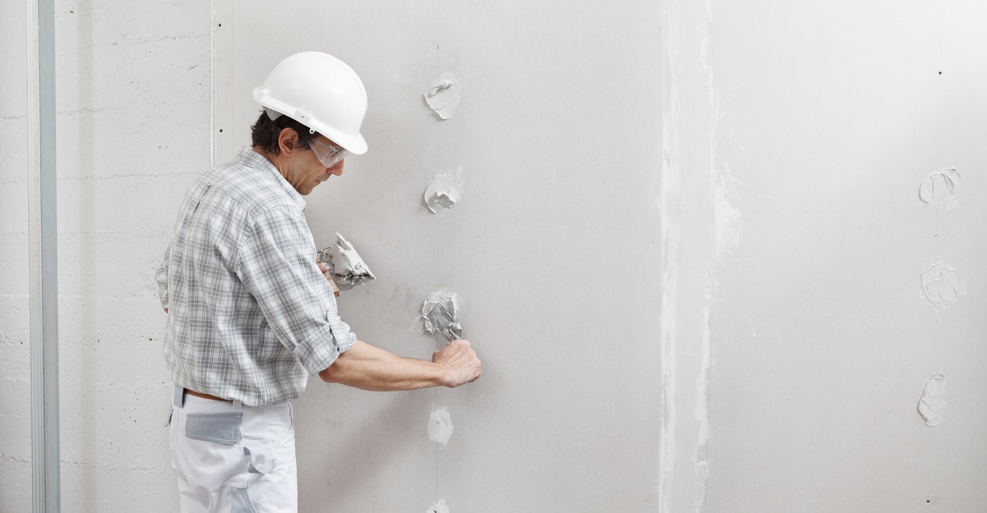 a man putting plaster on a drywall