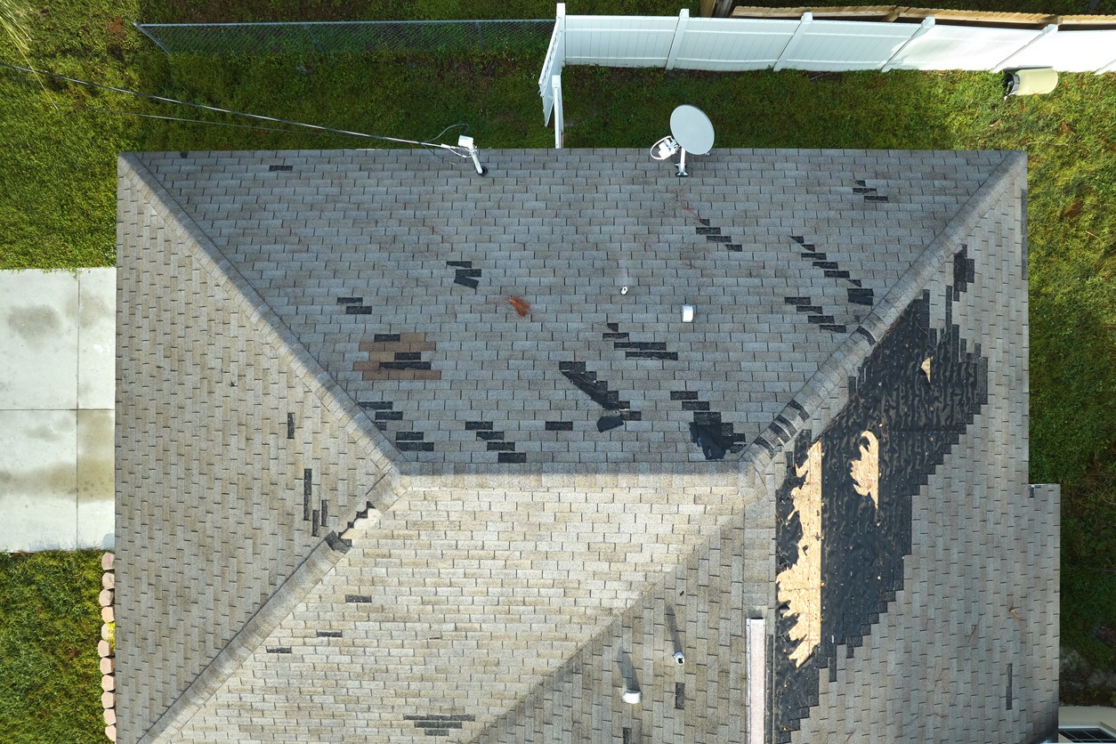a roof with a wind damaged shingle roof