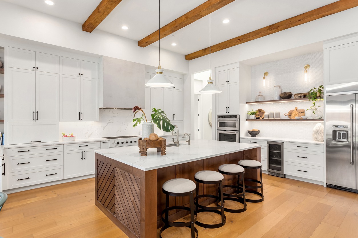 a beautiful kitchen in new luxury home with island, pendant lights, and hardwood floors