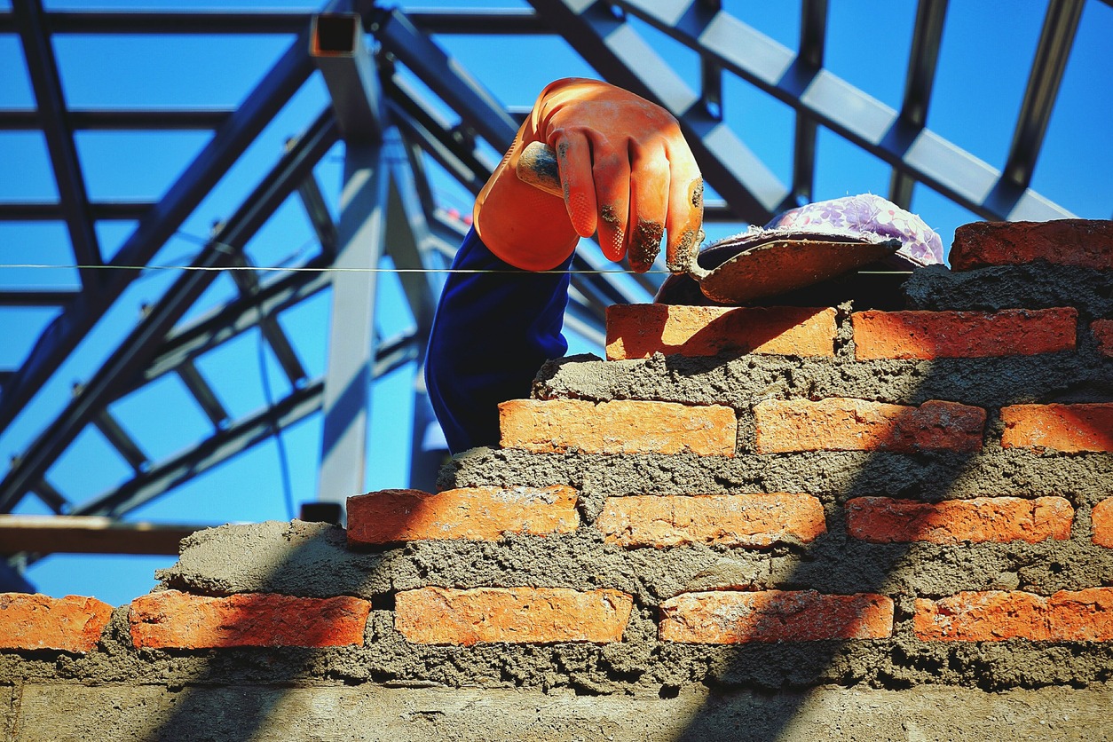 a bricklayer using trowel to build brick wall