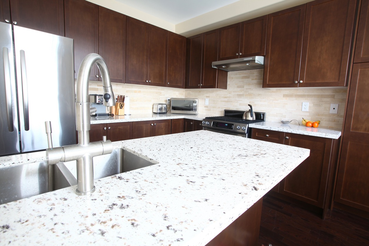 a home kitchen with quartz countertops and chestnut cabinets