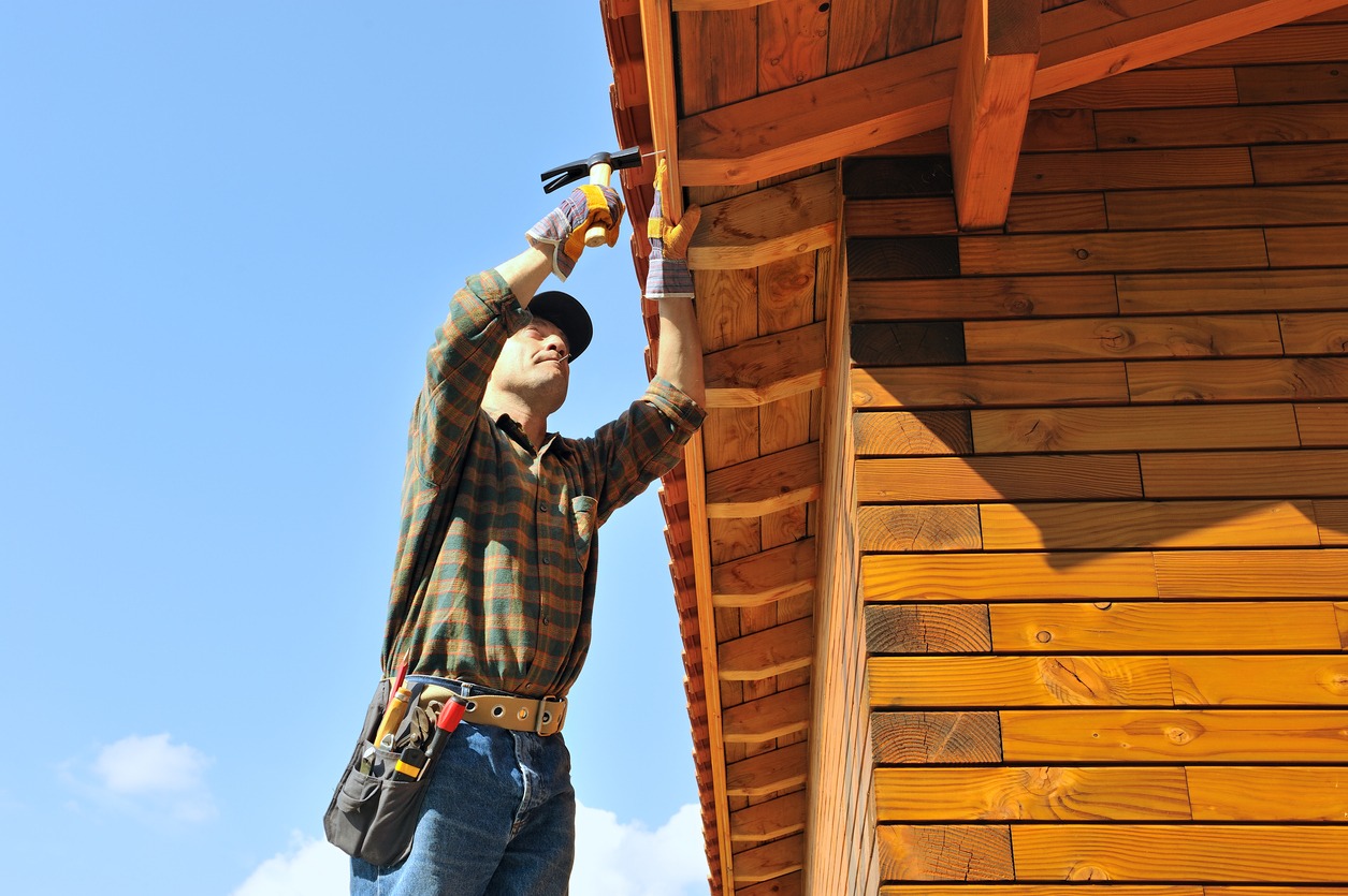 a man doing repair by the roof of an adobe home