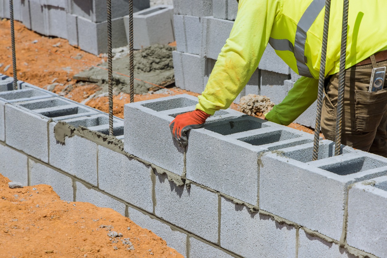 a mason in the process of mounting a wall of aerated concrete blocks