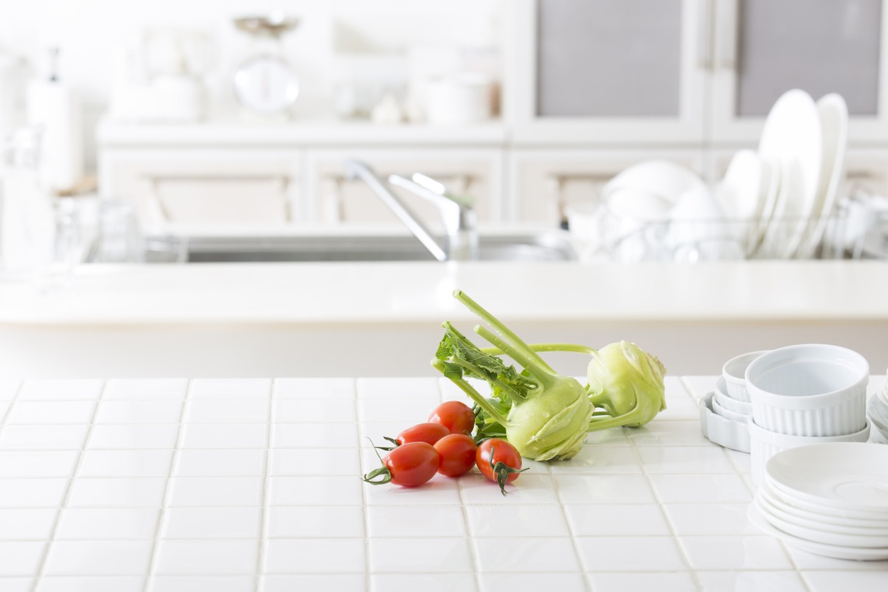 a white, porcelain tile countertop with vegetables on it