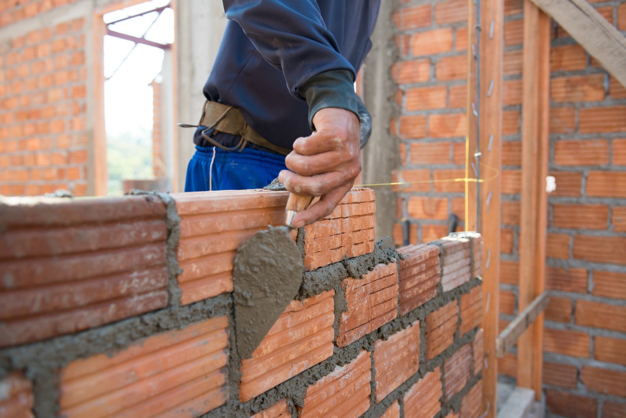 a worker building masonry house wall with bricks