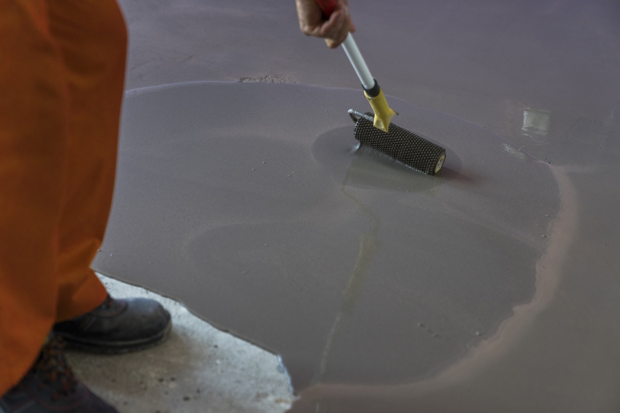 A man paints the concrete floor with a roller