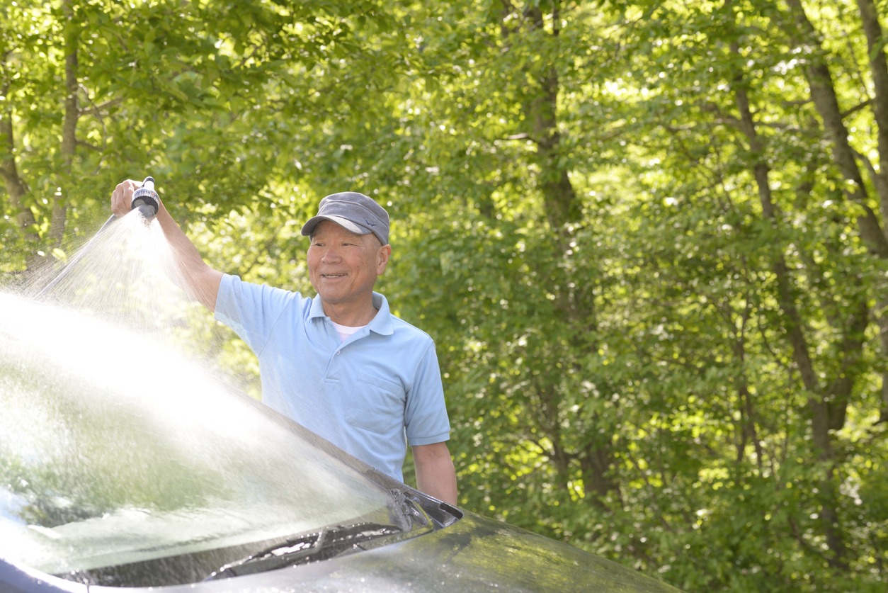 A senior splashing the car roof with cold water