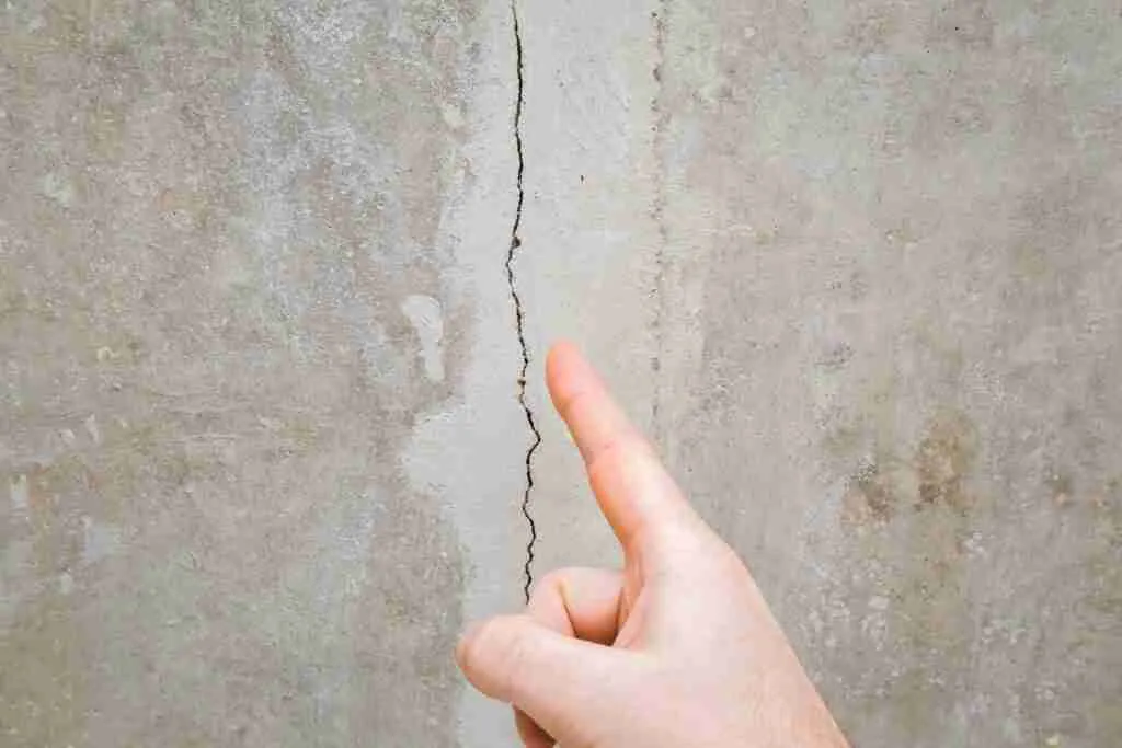 Man hand finger pointing to cracked ceiling. Building problem and solution concept. Closeup.