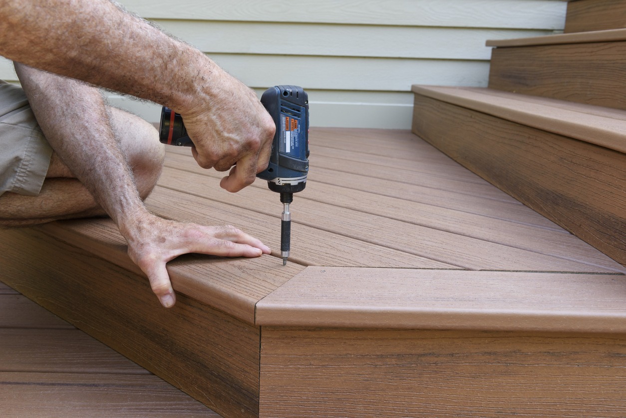 Close-up of worker using drill to install new porch decking.