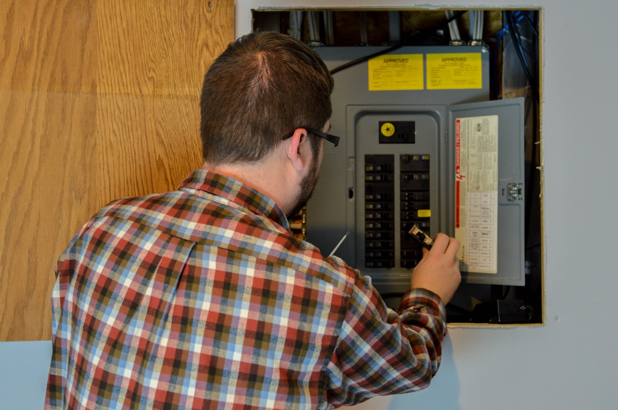 handyman/repairman inspecting an electric box/circuit breaker in a residential home.