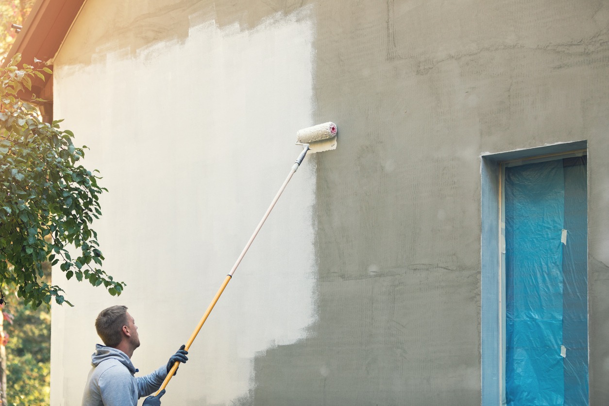 House painter painting building exterior with roller